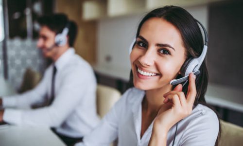 How can I help you? Beautiful call center workers in headphones are working at modern office.
